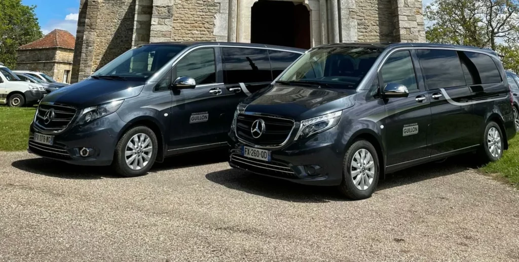 Deux corbillards Mercedes noirs de l'agence funéraire stationnés devant une église