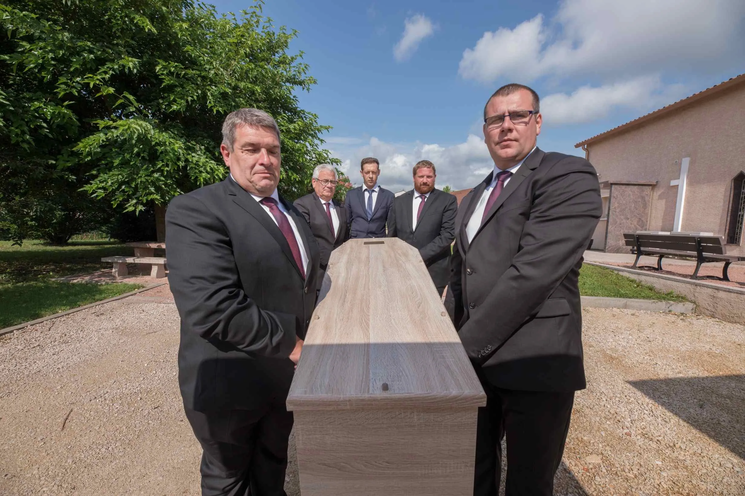 Porteurs funéraires en costume portant un cercueil