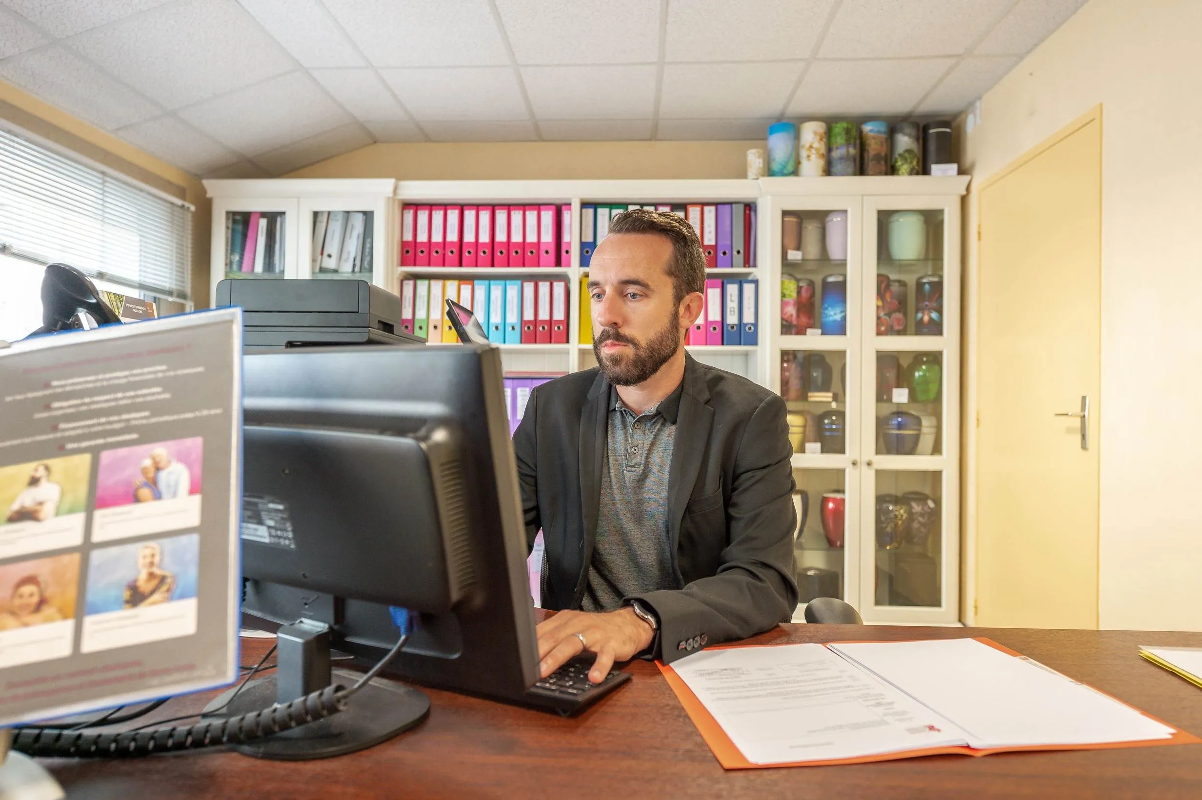 Conseiller funéraire travaillant sur ordinateur et gérant des dossiers administratifs en agence